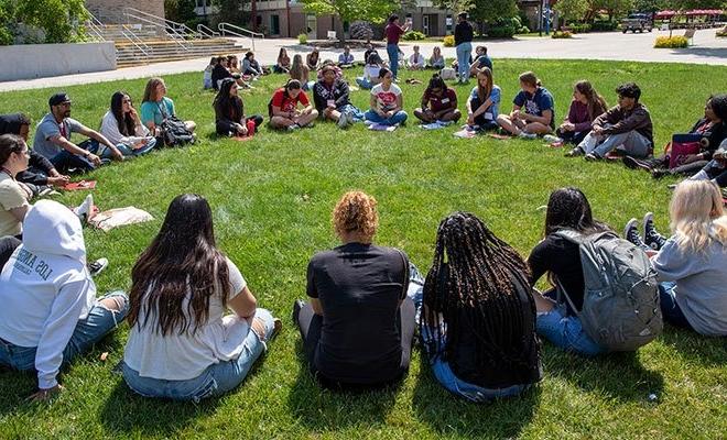 Group of students sitting in a circle on the grass at orientation